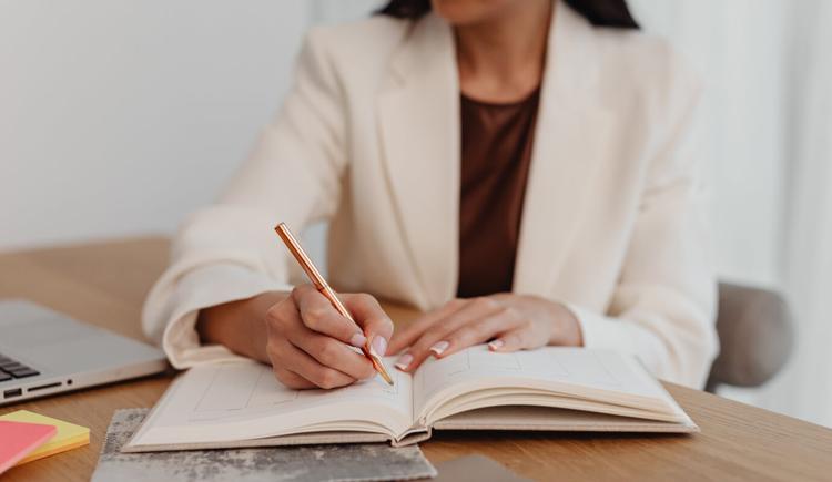 A female therapist writes out the SOAP note assessment section in her notebook