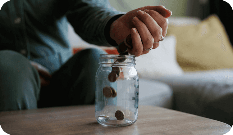 A therapist puts coins into a jar as they think about their private practice's financial health.