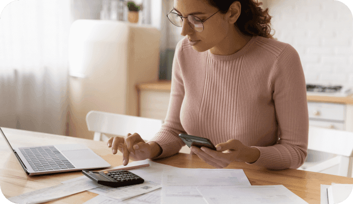 A female therapist uses her calculator while sitting at her laptop wondering about navigating private pay vs insurance clients