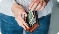 A therapy client takes out there wallet to pay in cash as part of a pay what you can model of paying their therapist