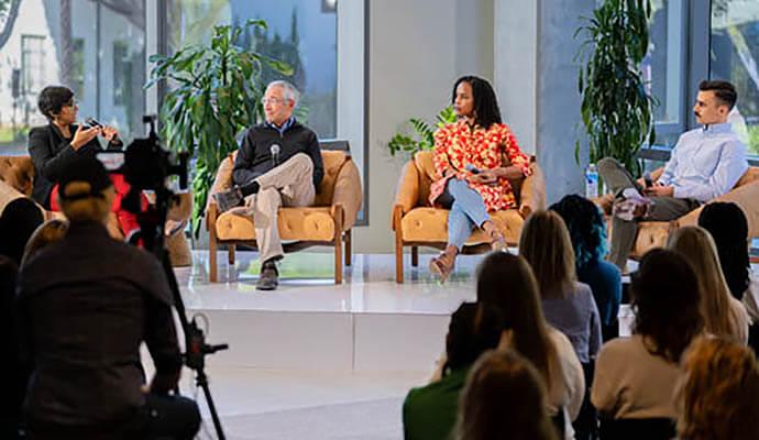 A panel of two women and two men are in conversation on a stage in front of an audience about the state of mental health in America at SimplePractice headquarters in California