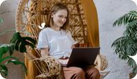A therapist sits down on a wicker chair with her laptop to fill out a Wiley Treatment Planner.