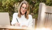 A woman is sitting outside working on a professional will template.