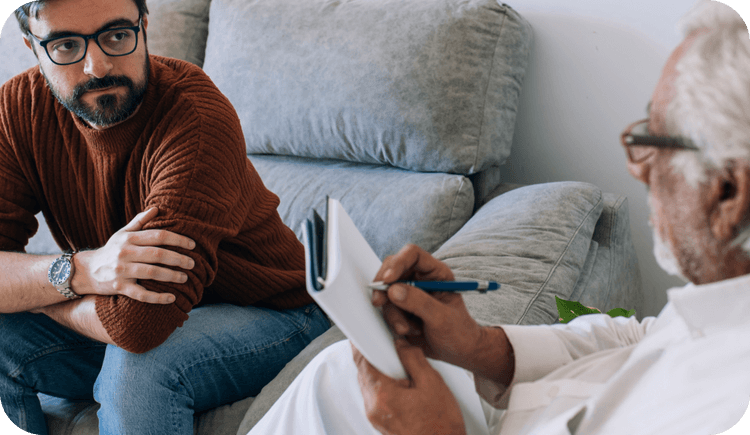 A client sits on the couch with his therapist who offers Medicare for mental health services