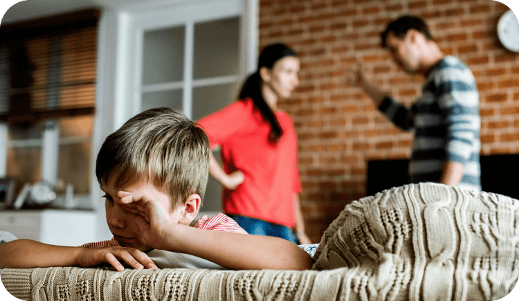 A family, two adults and one child, are in a room, the two adults are engaged in an argument while the child faces away from them on the couch, hand covering his face. Family therapy interventions can strengthen a variety of relationships. This article shares family therapy techniques you can use with clients.