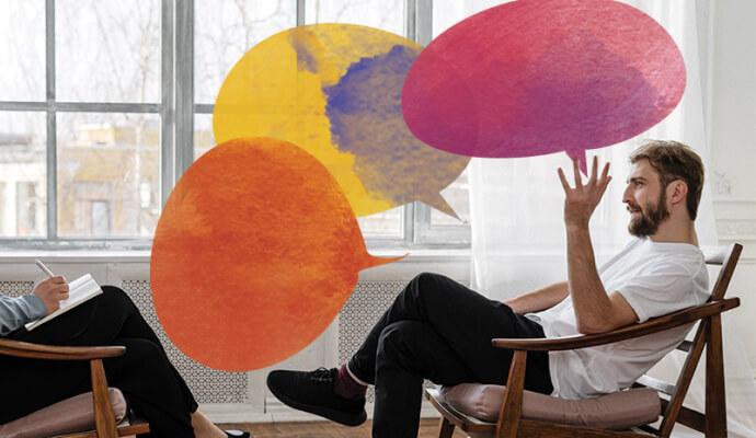 Image of a male client with colorful speech bubbles talking to his therapist as the therapist takes notes to help understand if a client is lying in therapy