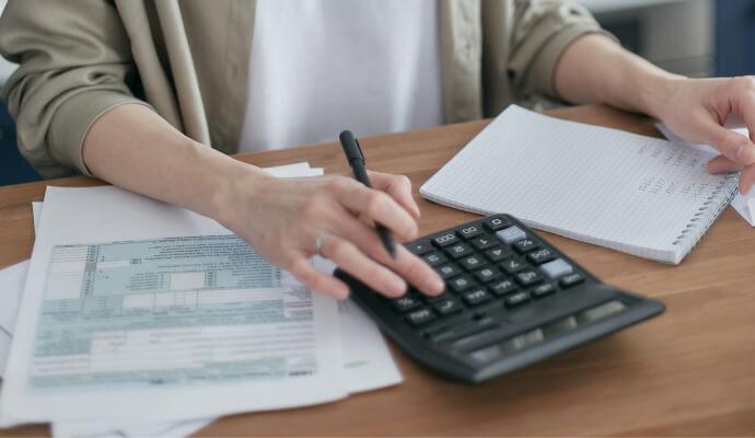Hands of a female therapist using a calculator while calculating her tax write-offs for therapists