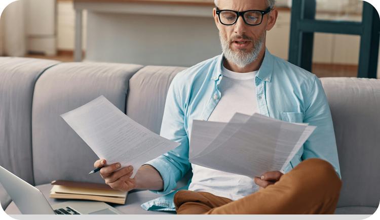 A therapist rifles through a stack of papers explaining various counselor liability insurance plans, as he looks for the right one for his practice.