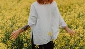 Woman outdoors in nature walking in a field of yellow flowers ponders how nature affects mental health