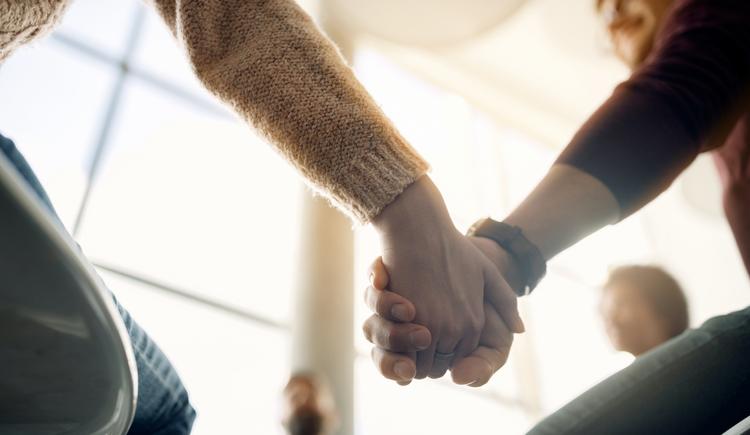 Clients link hands together in a circle, utilizing one of the motivational group therapy activities suggested in this article.