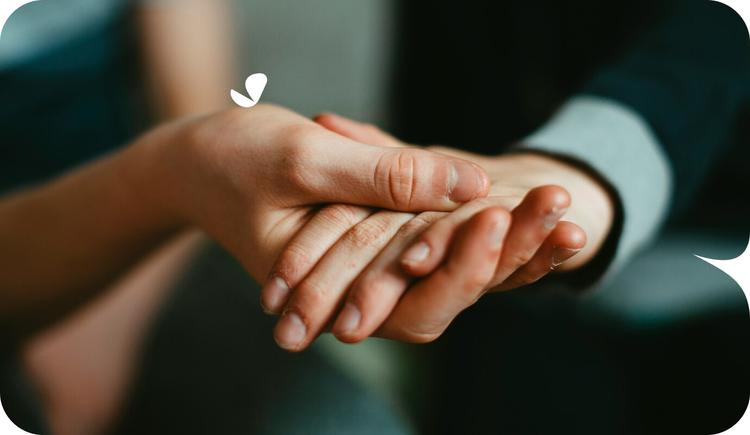 Handhold of two loved ones, while one encourages the to consider starting therapy.