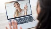A woman waves on a screen while on a video call.
