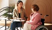 disabled woman in wheelchair conversing with therapist