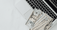 Laptop and money that represents a therapist working on a good faith estimate based on the no surprise act
