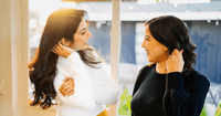 Therapists Prerna Rao and Valeri Trezise standing in a well-lit room and smiling at each other.