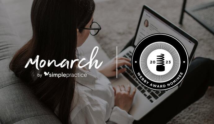 A woman with glasses looks at her laptop and learns Monarch directory by SimplePractice is nominated for a Webby Award and needs everyone's votes to win a People's Choice Award