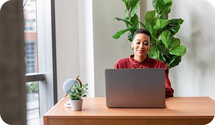 A woman therapist sits at her desk looking at her laptop to research the difference between ICD and CPT codes.