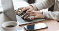 Close up of a person's hands on a computer searching for electronic soap note software, features to look for & how to transition from paper