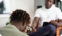 A male therapist works with clients in a substance use disorder recovery group