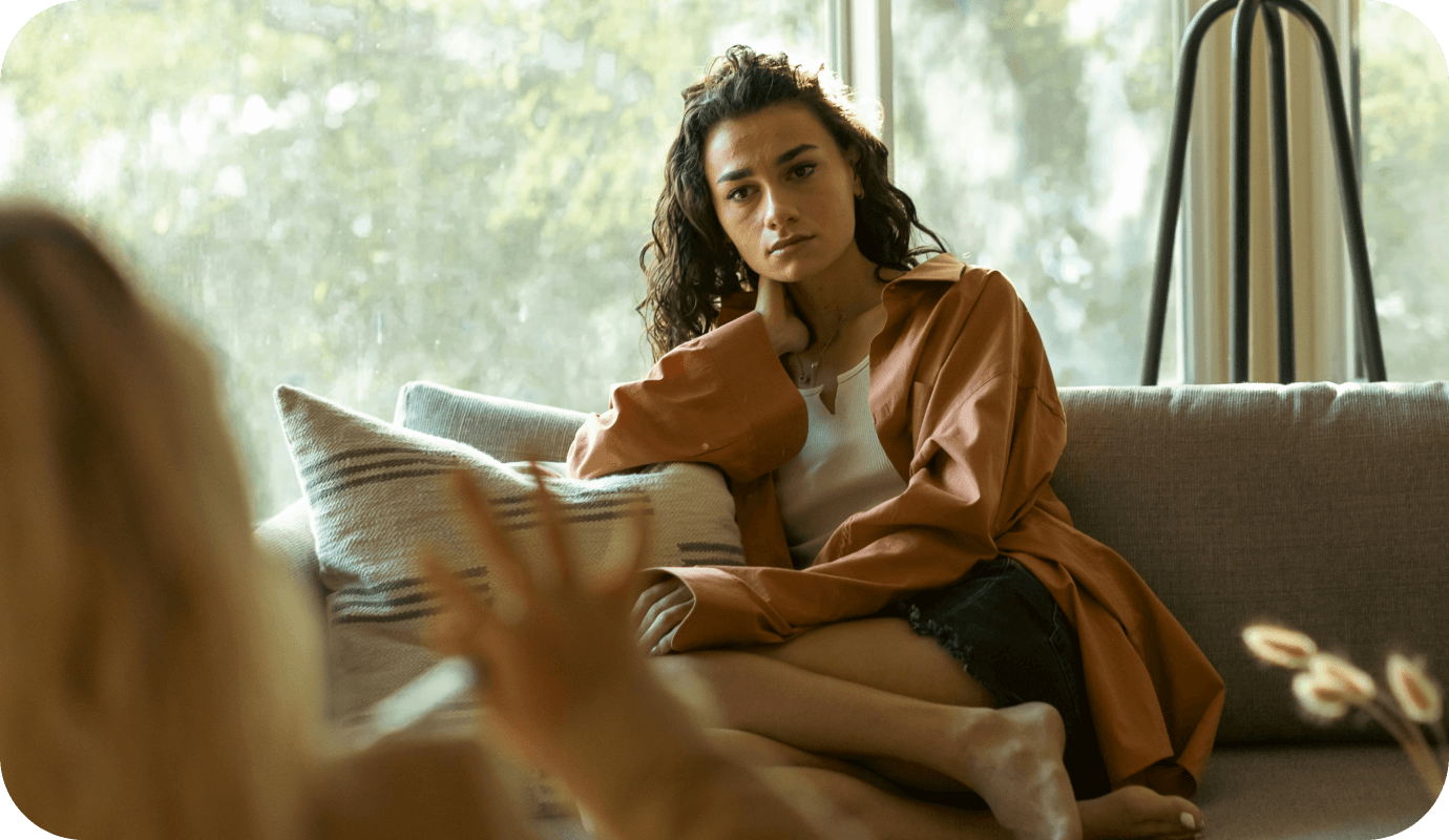 A client sits on a couch speaking with a therapist and they are wondering about what therapist abbreviations and psychologist abbreviations stand for