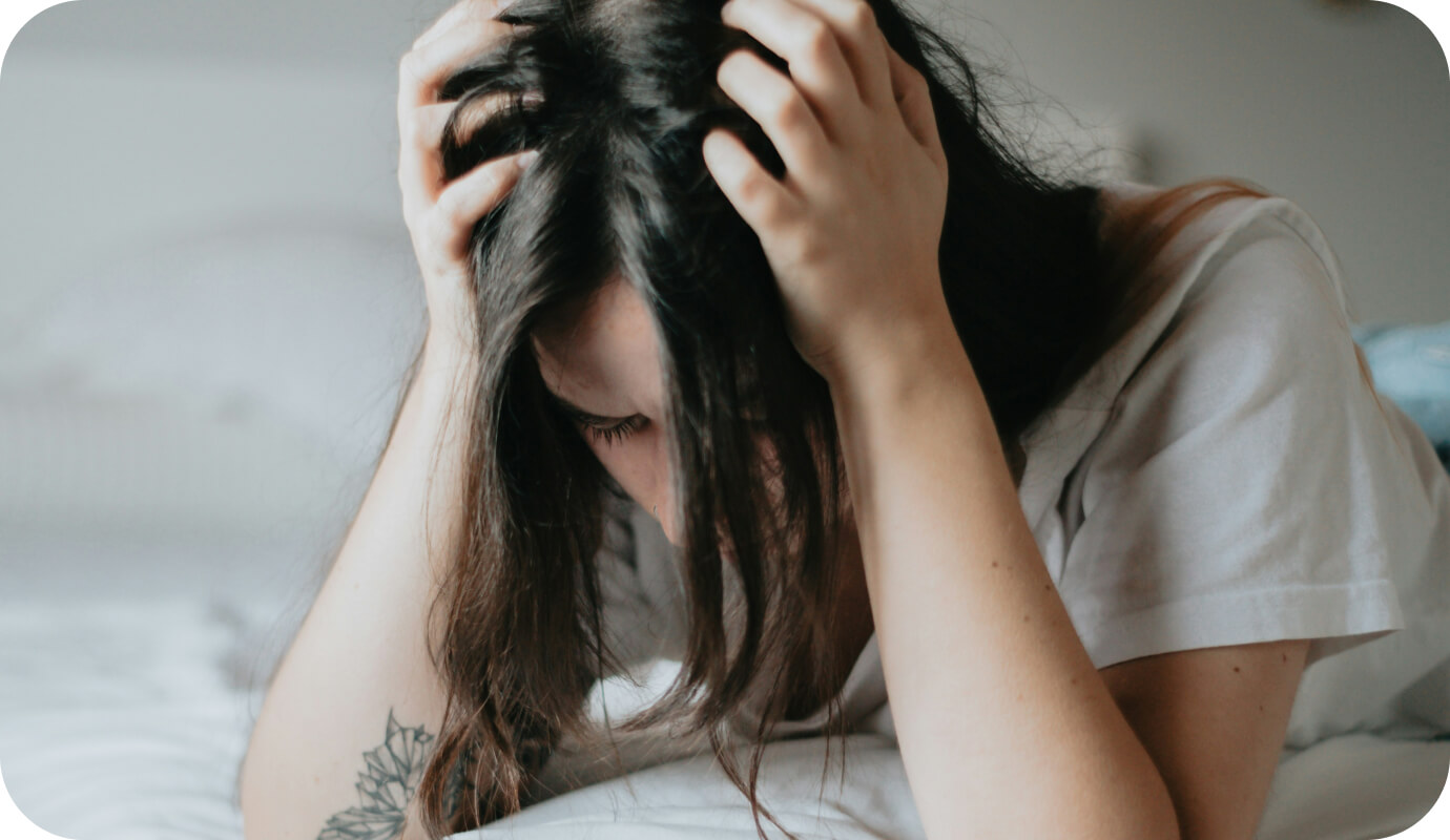 A client holds their head in their hands-frustrated as they struggle through one of the 5 stages of psychosis.