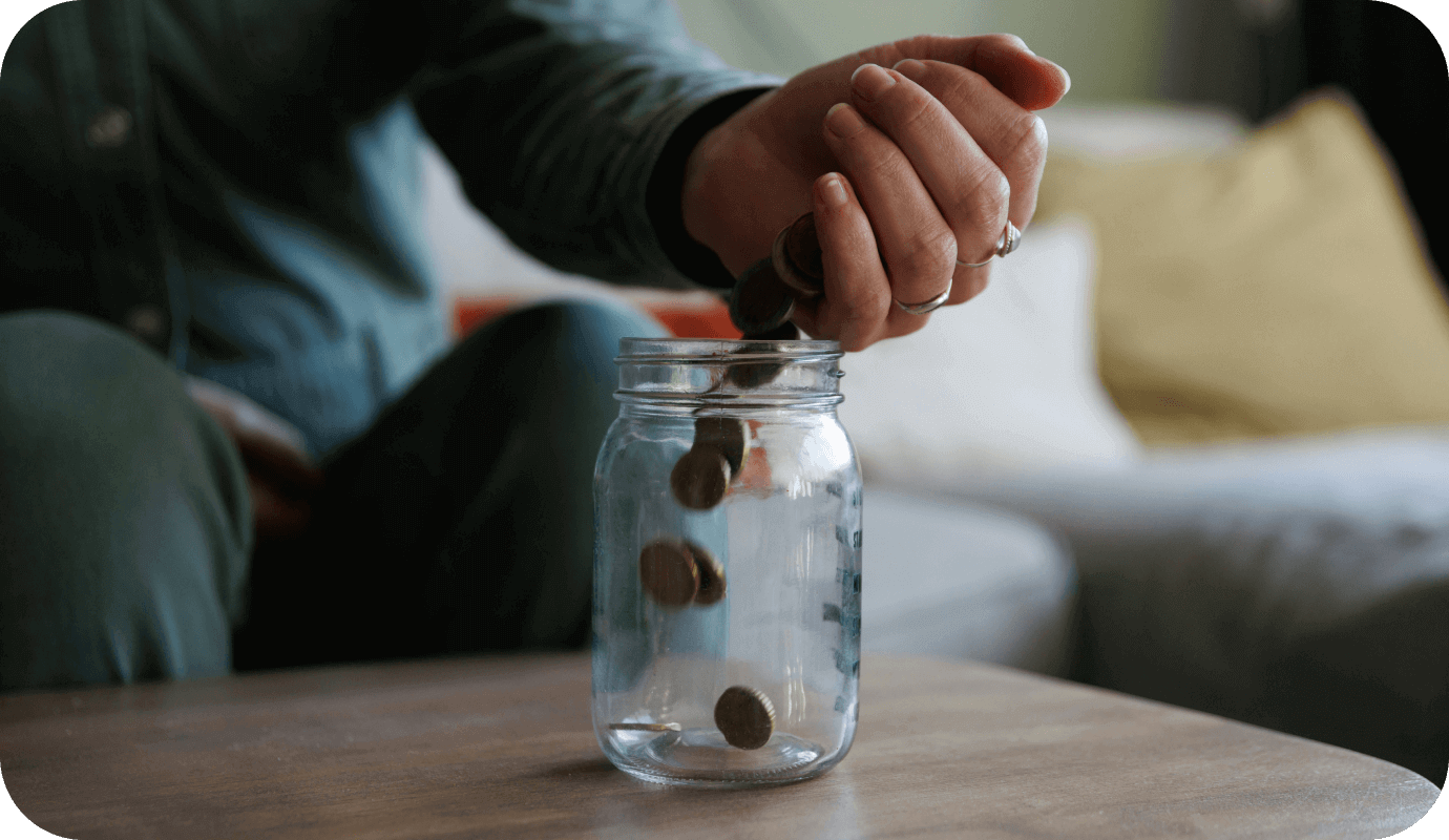A therapist puts coins into a jar as they think about their private practice's financial health.