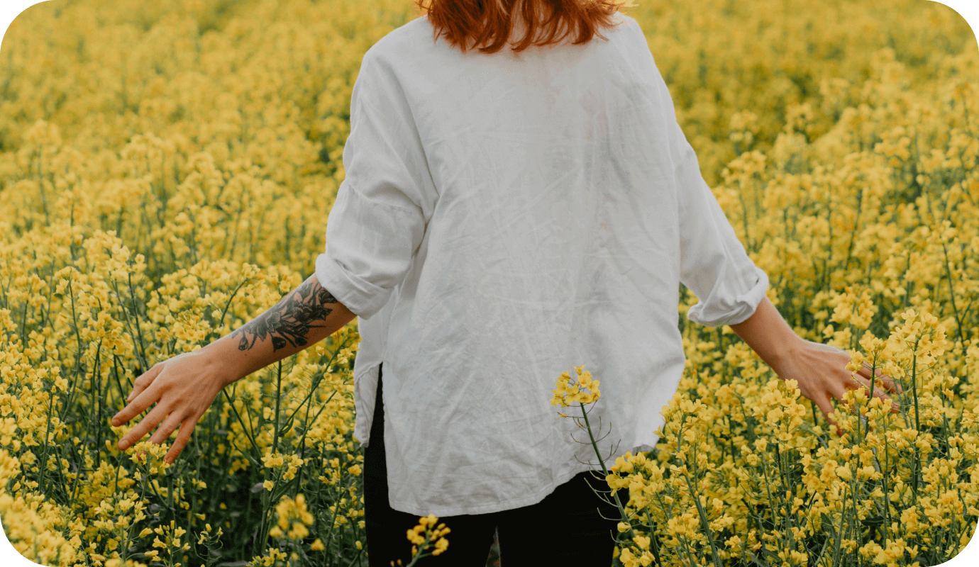 A therapist is outdoors walking in a field of flowers and it improves her mental health