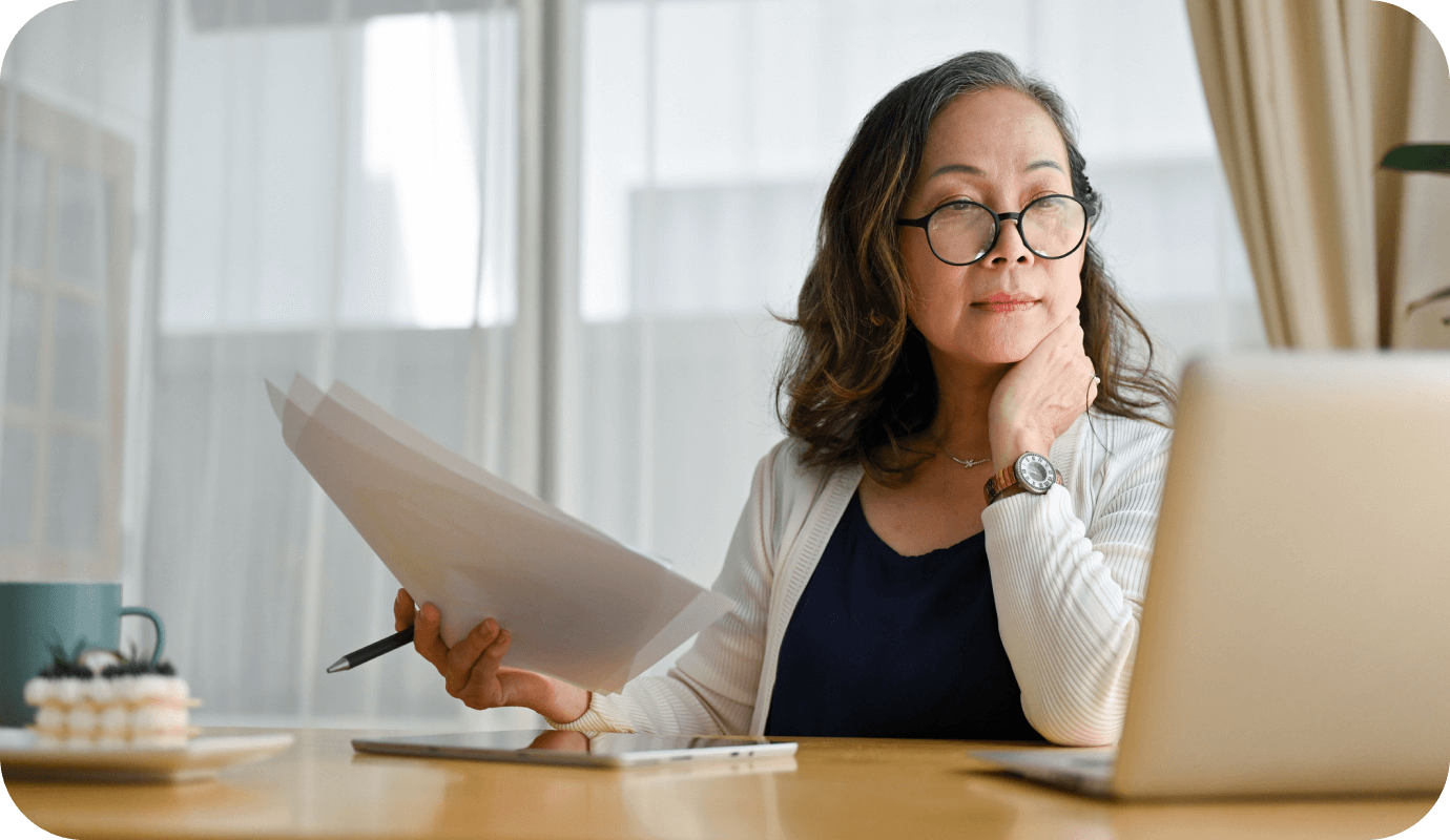 A therapist looks at her laptop and holds some paperwork while wondering how to get a raise in her insurance reimbursement rate.