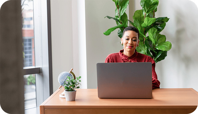A woman therapist sits at her desk looking at her laptop to research the difference between ICD and CPT codes.