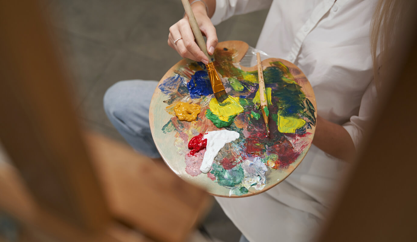 A female therapy client paints using multiple colors on an easel as an art therapy activity for anxiety and PTSD