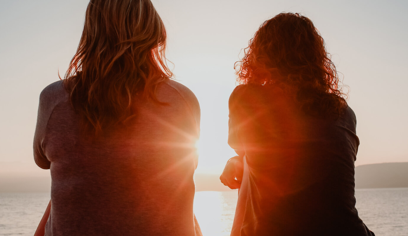 Two female therapists sit together in the sunset and discuss therapist burnout