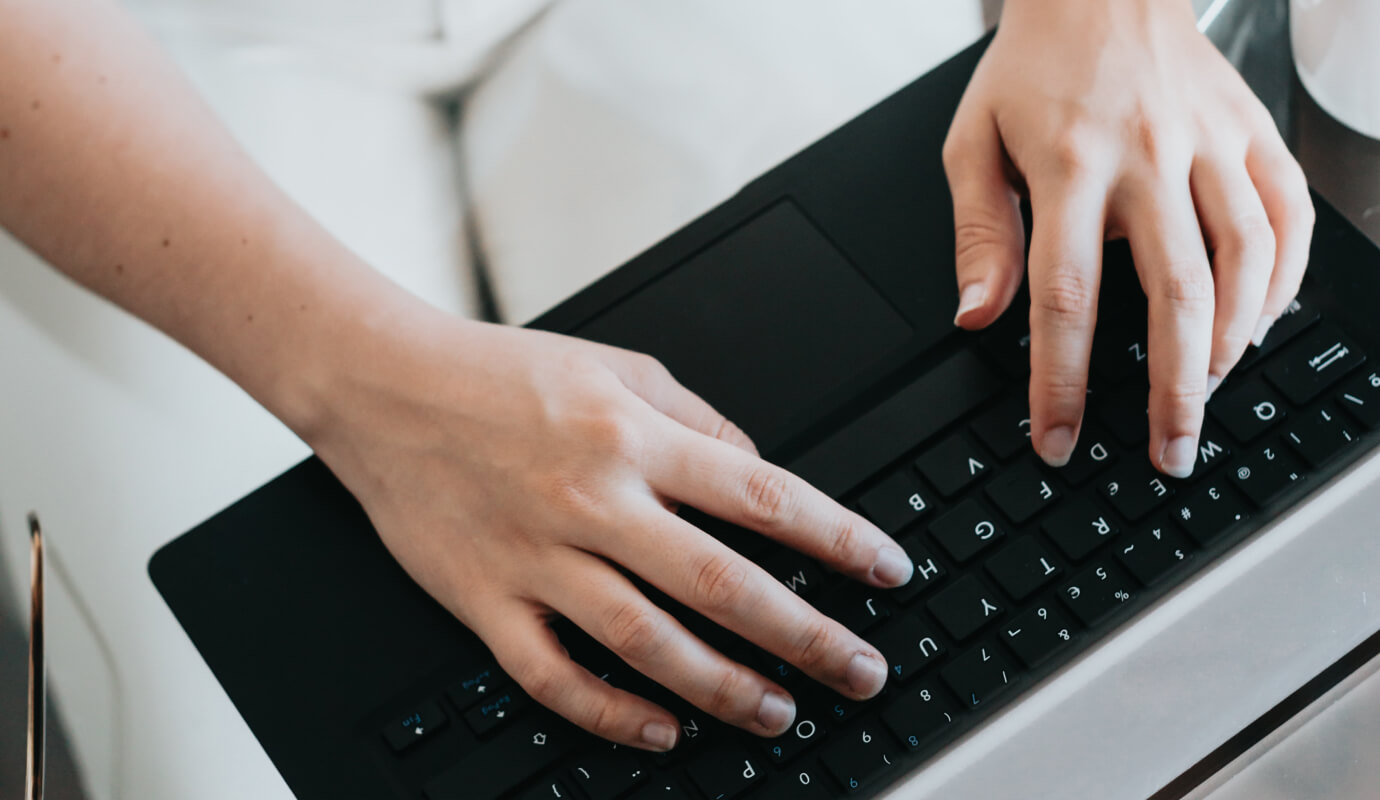 A therapist's hands type up social work progress notes on a keyboard.