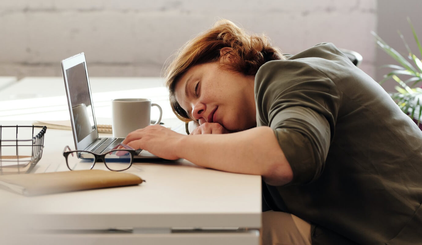 Female therapist who needs help learning how to overcome procrastination falls asleep at their desk