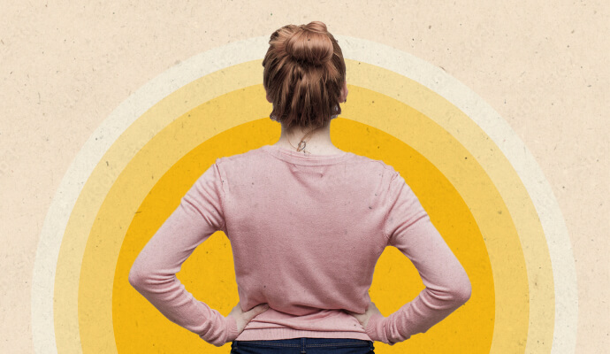 A woman standing with her hands on her hips in front of a yellow collage.