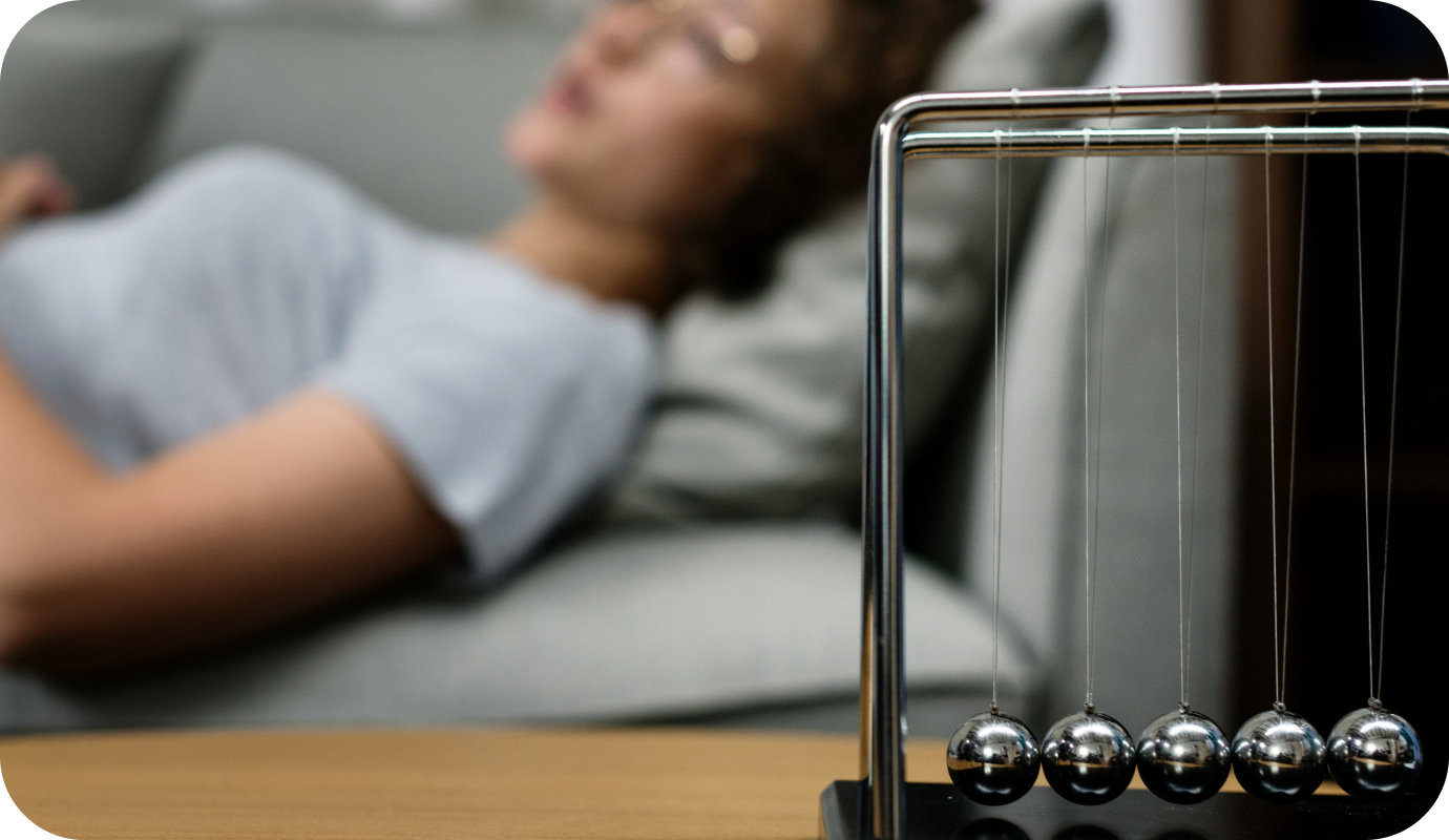 A patient lays on a therapists couch with her eyes closed at the beginning of a hypnotherapy session